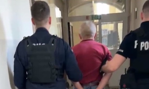 dwaj policjanci z zatrzymanym mężczyzną zakutym w kajdanki