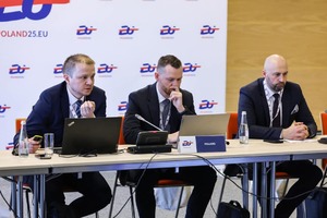trzech mężczyzn siedzi przy stole.