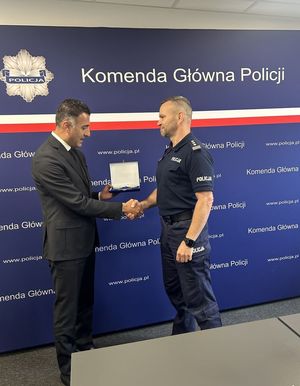 Mężczyzna wręcza policjantowi upominek.